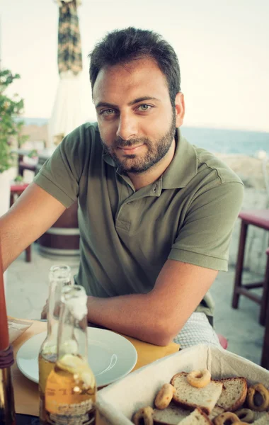 Junger Mann sitzt im Restaurant am Meer. — Stockfoto