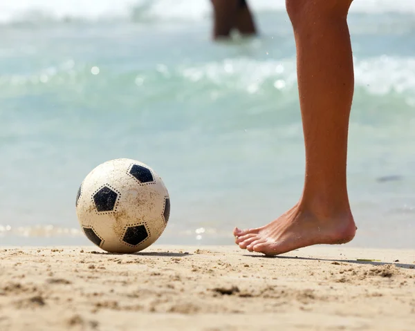 Крупный план мужской ноги, играющей в футбол на песке — стоковое фото