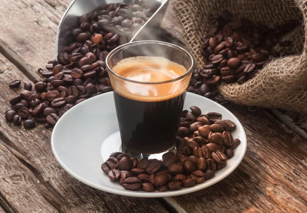 Espresso káva v sklenici s kávová zrna. — Stock fotografie