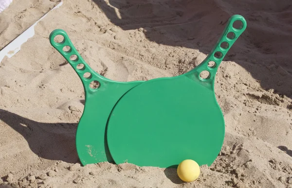 Две ракетки и мяч на песчаном пляже — стоковое фото
