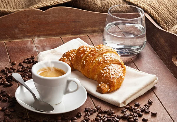 Espresso mit Croissant und Glas Wasser. — Stockfoto