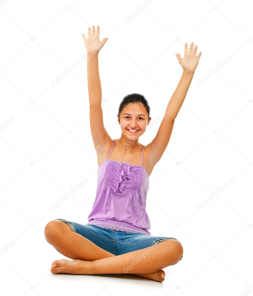 Sitting teenage girl while rejoices with arms up.