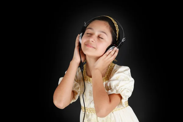 Menina jovem em vestido antigo enquanto ouve música com fone de ouvido — Fotografia de Stock