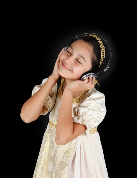 Menina jovem em vestido antigo enquanto ouve música com fone de ouvido — Fotografia de Stock