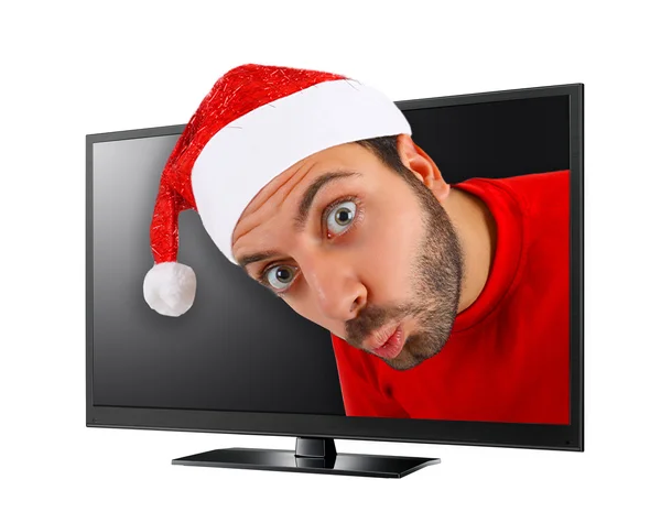 Young man with hat of Santa Claus comes out from the TV. — Stock Photo, Image