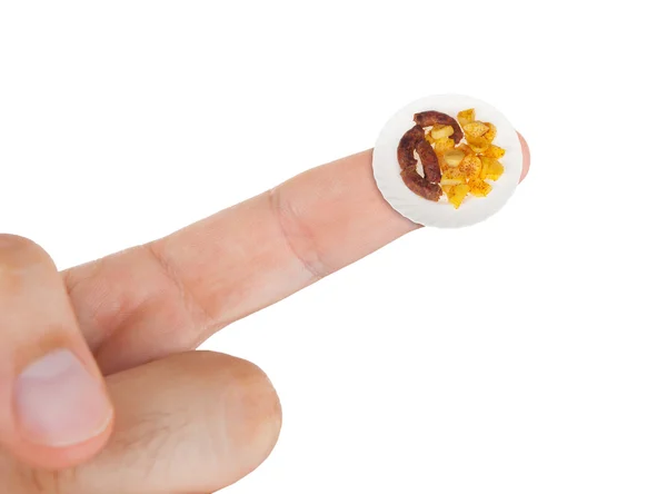 Блюдо с сосисками с картошкой в миниатюре на указательном пальце — стоковое фото