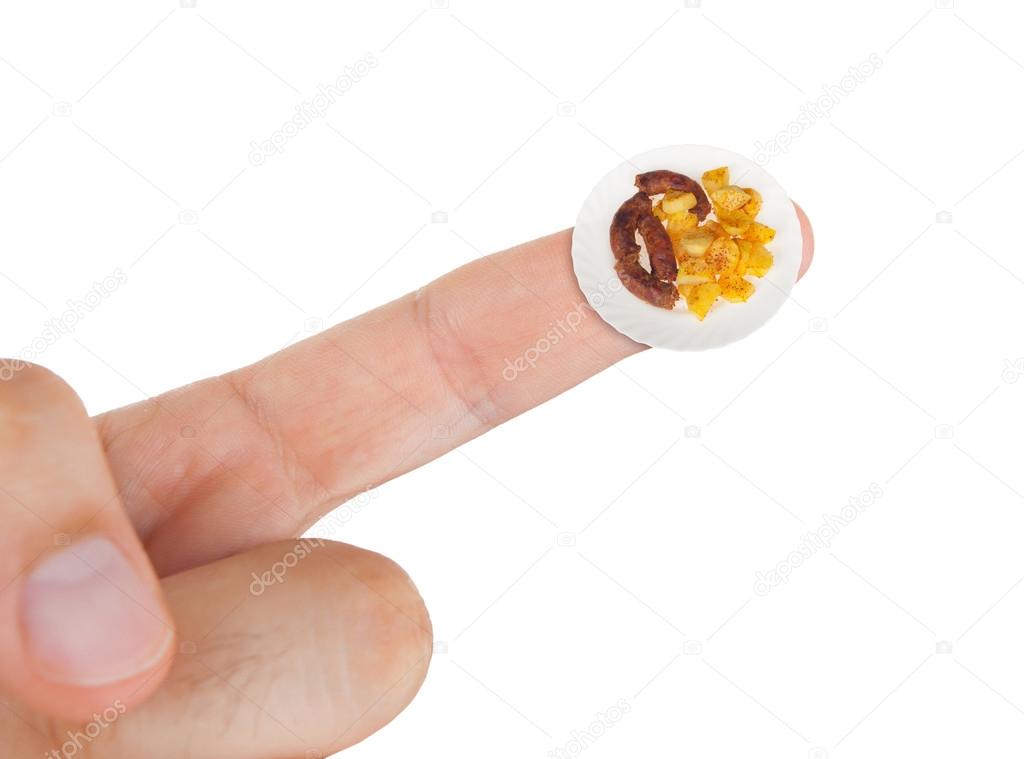 Dish with sausages with potatoes in miniature on index finger