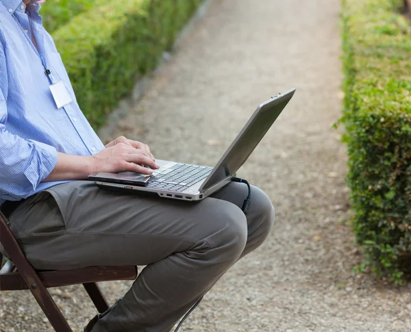 Businessman holding a laptop on his knees — Stock Photo, Image