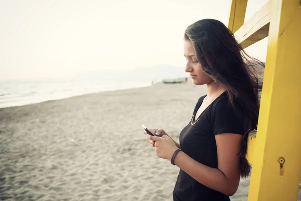 Młoda nastolatka podczas przy pomocy ten smartphone na plaży — Zdjęcie stockowe