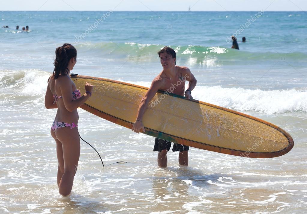 Surfer explains theory of surfing to a young woman