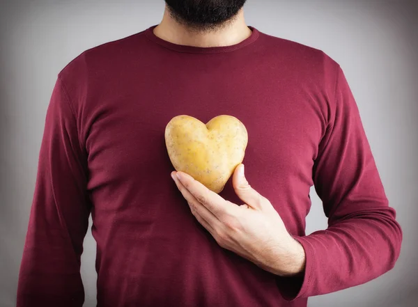 Man met een aardappel gevormd hart op zijn borst. — Stockfoto