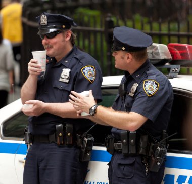 Two police officers while drinking a cup of coffee in NYC. clipart