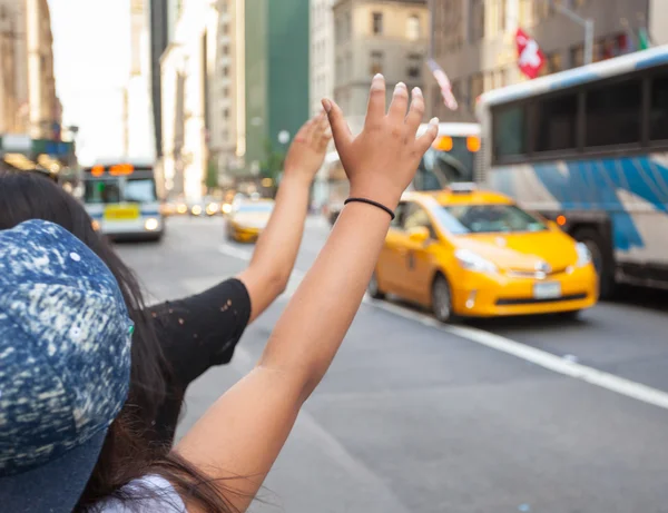 Tourists call a yellow cab in Manhattan with typical gesture — Stockfoto