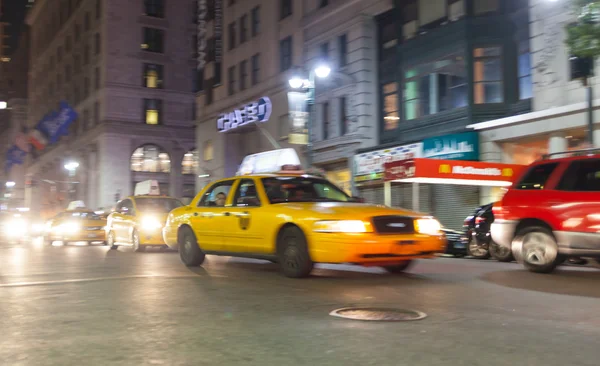 Gelbes Taxi nachts in New York City in Bewegung blu. — Stockfoto