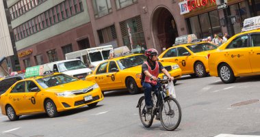Cyclist in traffic between the yellow cabs in Manhattan, NYC.