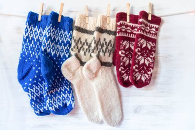 Örgü yün çoraplar ve tahta arka planda mandallara asılan eldivenler. Fransa bayrak renkleri klasik süsleme. Kış ve Noel konsepti