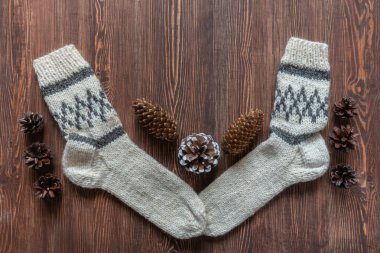 Soğuk mevsim için yün çoraplar ve kahverengi eski ahşap arka planda çam kozalakları. Beyaz ahşap yüzeyde kış için sıcak yün çoraplar, metin için kopya alanı