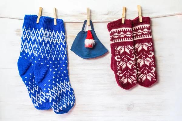 Örgü yün çoraplar, eldivenler ve koruyucu maske takan Noel Baba oyuncağı, ahşap duvarda asılı. Güvenli bir Noel konsepti. Kopya alanı olan klasik Noel dekorasyonu