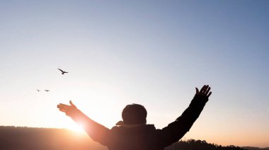 Özgürlük kavramı: Bir adam dağın tepesinde durur ve Tanrı 'ya ibadet etmek için ellerini kaldırır.