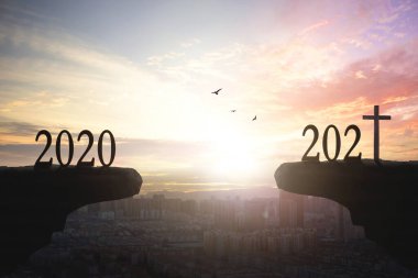 2021 konsepti: 2021 yılının silueti ve şehrin günbatımı arka planıyla dağları aşmak