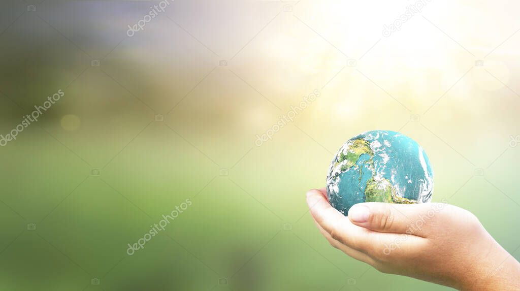 Hands Holding earth global In Lush Green Environment With Sunlight . Elements of this image furnished by NASA