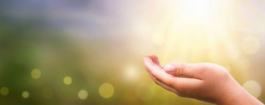 İnsan eli, gün batımının bulanık arkaplanı üzerinde açık.