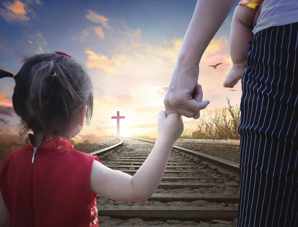 Praise and worship concept: Child\'s hand holding mother\'s finger on blurred The cross of jesus christ background.