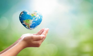 Dünya Çevre Günü konsepti: İnsan palmiyeleri açar ve kalp şeklindeki dünyayı bulanık mavi gökyüzü ve su arka planında sürükler. Bu görüntünün elementleri NASA tarafından desteklenmektedir
