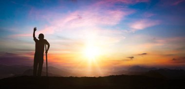 Silhouette of man in mountains under beautiful sky at sunset
