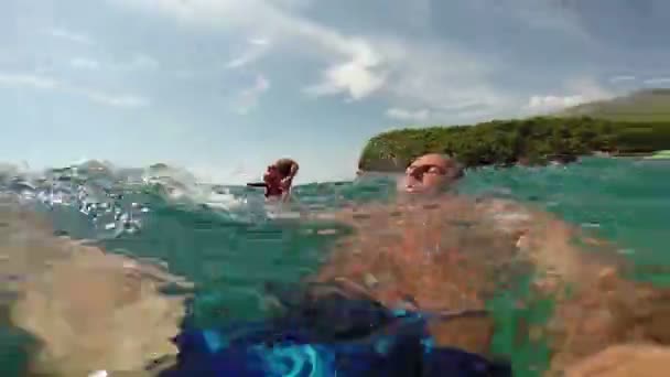 Mann schwimmt im kristallklaren Meerwasser mit roten Seesternen in der Hand — Stockvideo