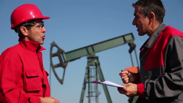 Dwóch Inżynierów Ropy Naftowej Omawiających Podpisujących Dokumenty Przed Studnią Naftową — Wideo stockowe