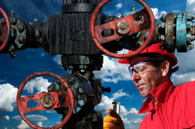 Petrol işçisi petrol ve gaz kuyusunu onarırken mavi gökyüzü ve arka planda beyaz bulutlar