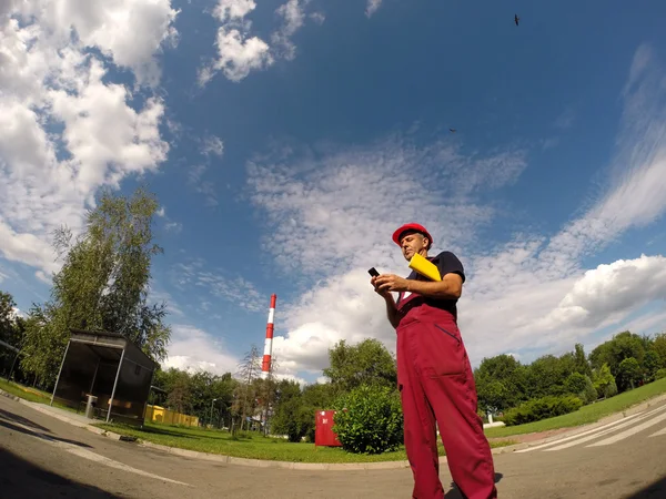 Industriarbetare tittar på sin mobiltelefon — Stockfoto