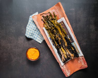 Grilled spring onions with romesco sauce, cenital view clipart
