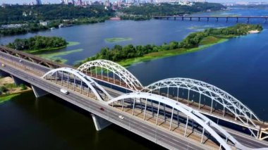 Güneşli bir günde öğleden sonra Kyiv 'deki Dnipro nehrinin karşısındaki demiryolu köprüsünün panoramik çekimi