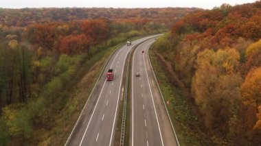Çevre yolunda trafik - Sarı ağaçların arasında otoyol boyunca araba ve kamyonlarla uçmak.