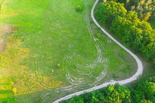 日没の森の端に湾曲した未舗装の道路-空撮 — ストック写真