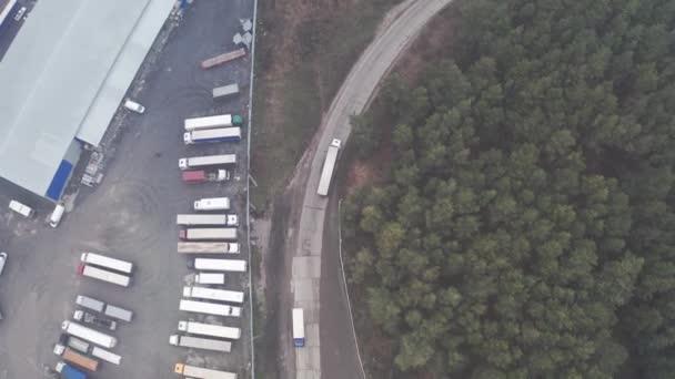 Un camion avec une remorque part d'un terminal logistique avec un parking pour camions. — Video