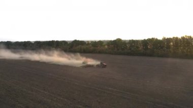 Traktör tarladaki toprağı işliyor ve toprağa gübre uyguluyor. İnsansız hava aracı yörüngesi atışı.