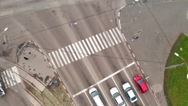 車は市内の大きな交差点近くの横断歩道を通って移動します-ドローンオーバーヘッドズームインショット. — ストック動画