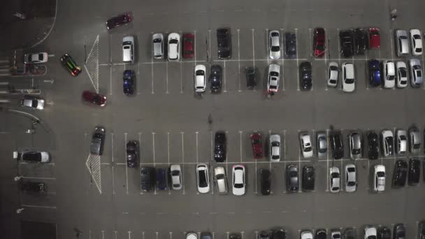 Pohyb aut na parkovišti u supermarketu v noci - nad hlavou drone shot. — Stock video