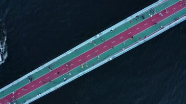 İnsanlar nehir boyunca bisiklet yolu olan yaya köprüsünde yürüyorlar - tepeden aşağıya doğru.