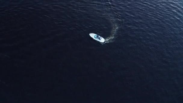 Witte kleine motorbootje beweegt in een cirkel en draait zich om met een spoor op het diepblauwe water — Stockvideo