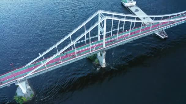 As pessoas caminham em uma passarela sobre um rio com uma barcaça de carga cheia de areia Drone tilt Down shot — Vídeo de Stock