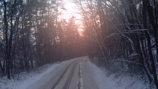 Strada invernale attraverso la foresta al tramonto. Dolly in colpo di una strada invernale attraverso foresta misteriosa. — Video Stock