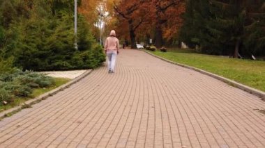 Kadın sonbaharın ilk günlerinde kaldırımda yürür - Yavaş Hareket