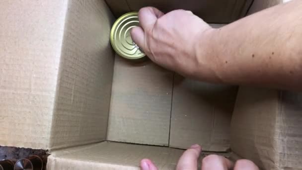 Muž sbírá krabici humanitární pomoci pro potřebné: rýži, obiloviny, konzervy v plechovkách. — Stock video