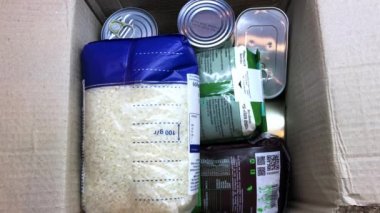 Gönüllü, ihtiyacı olanlara yardım etmek için bir kutu yiyecek topluyor.