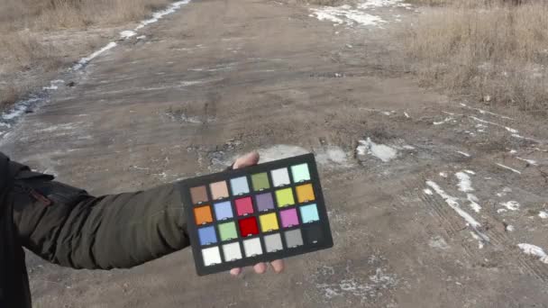 Color Checker i handen på en man på gatan i den kalla årstiden — Stockvideo