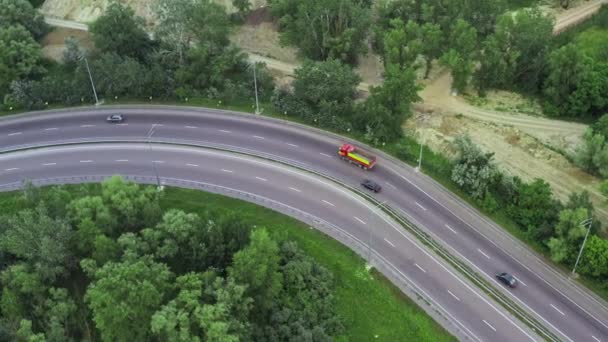 緑の葉の間の高速道路の車線に沿って車やトラックが移動します-ロケットドローンショット — ストック動画